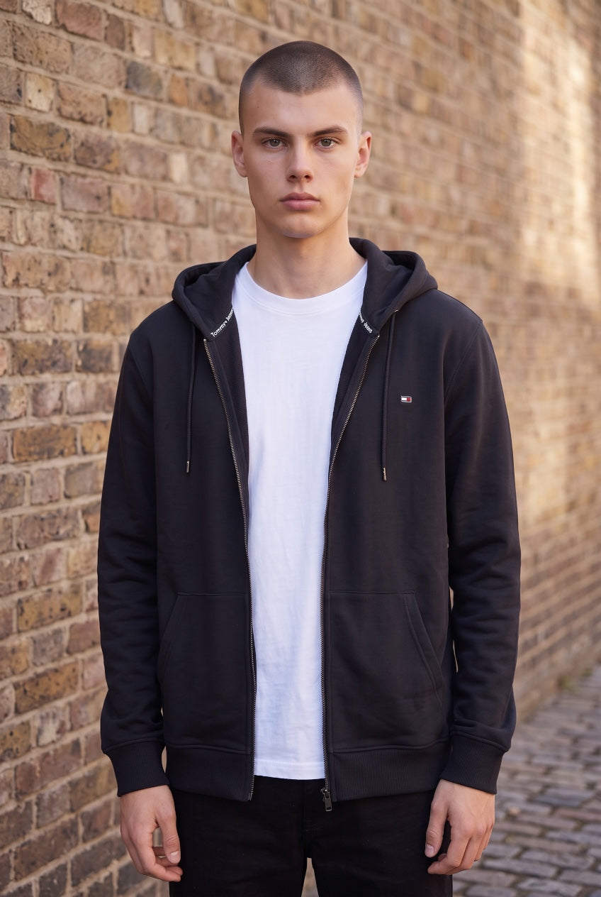 Black zip-up hoodie with hood and TOMMY JEANS flag logo, worn on a model