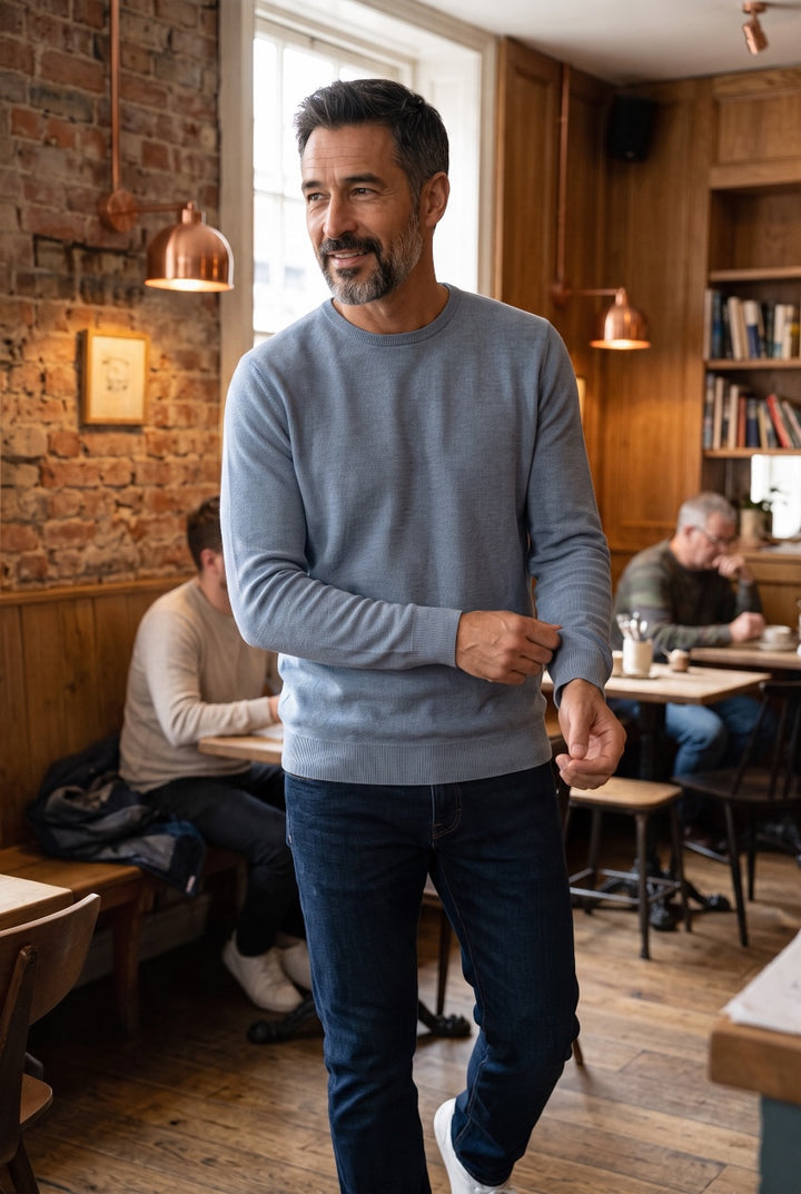 Man wearing a blue crew-neck sweater with long sleeves and ribbed cuffs and hem