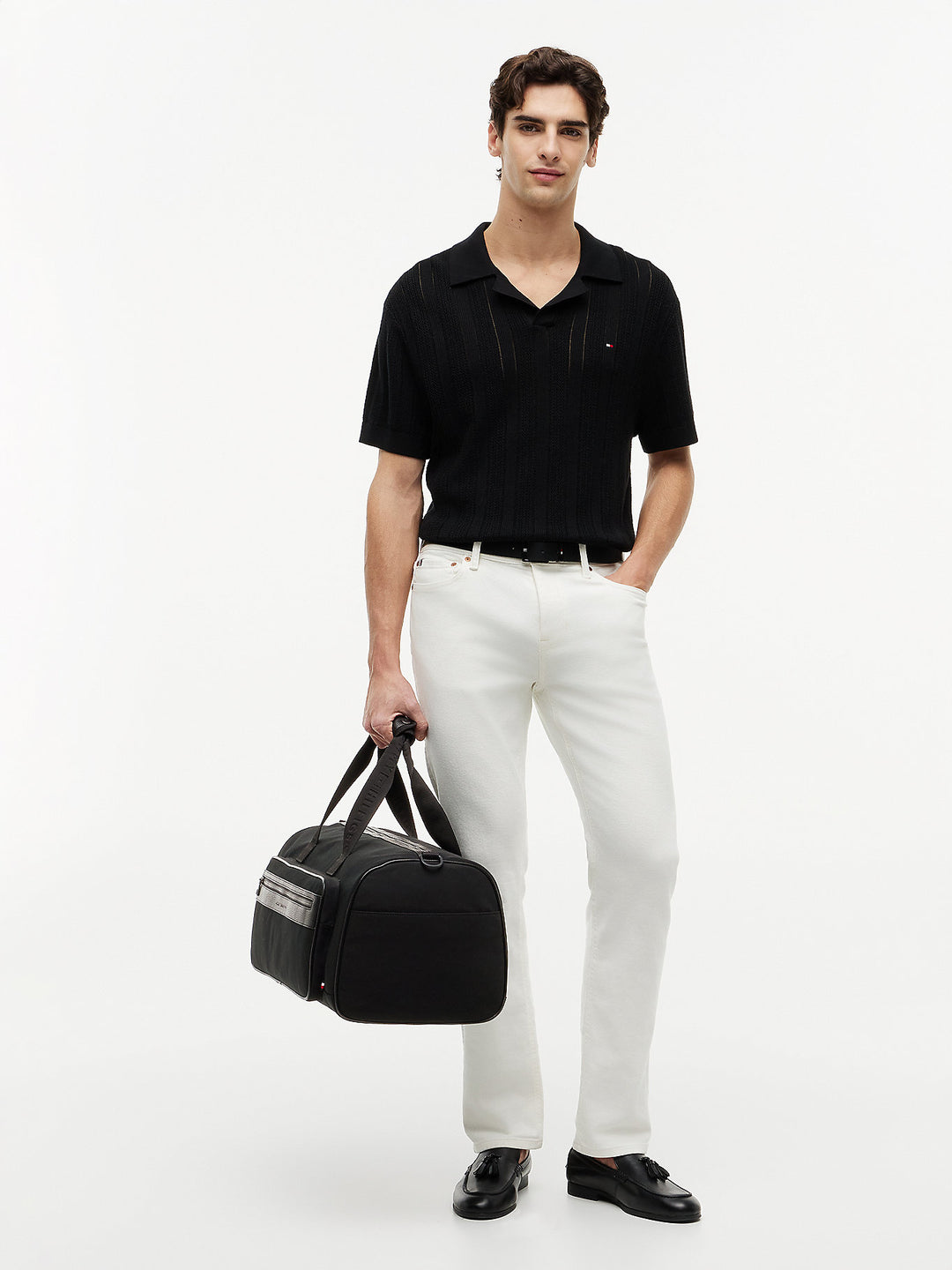 Black duffle bag on model with short handles and front zip pocket