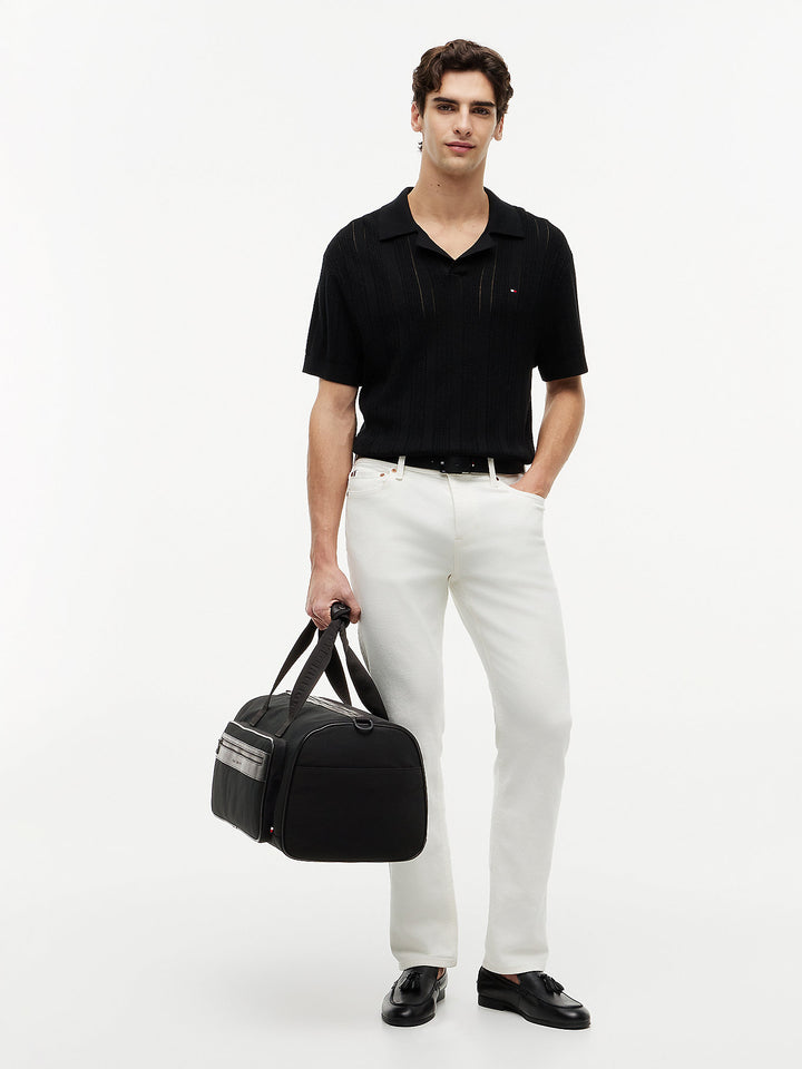 Black duffle bag on model with short handles and front zip pocket