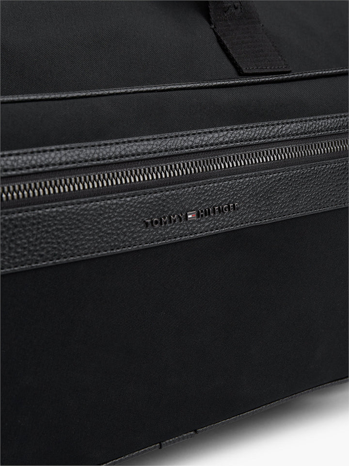 Black textured duffle bag with TOMMY HILFIGER logo and zippered top opening