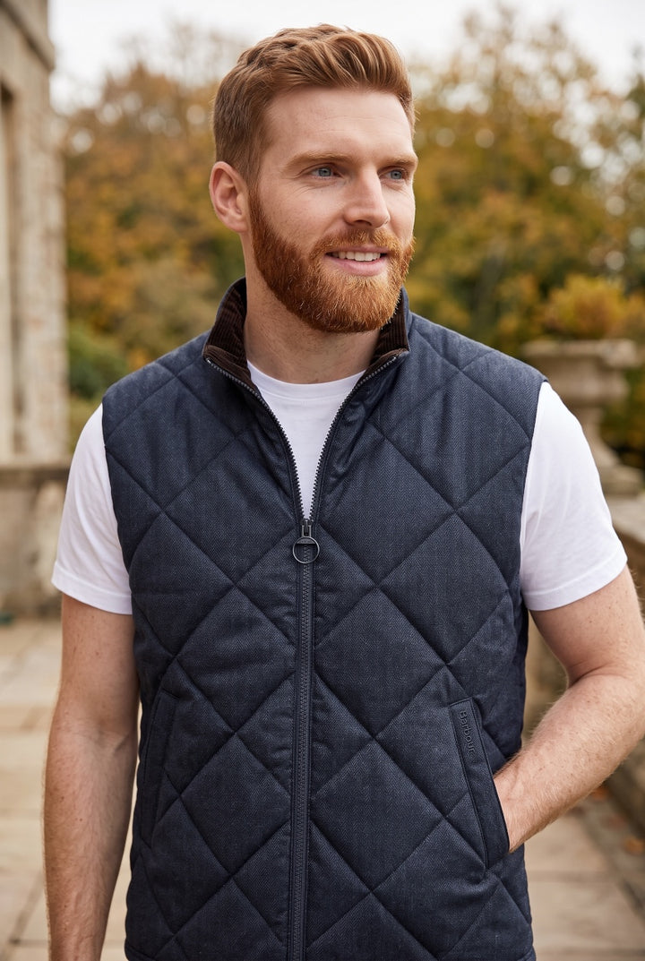 Barbour navy quilted gilet with stand collar and zip front, close-up on wearer