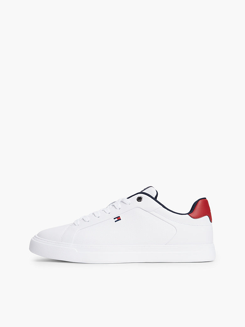 White low-top sneaker with navy trim, red heel detail, lace-up closure.