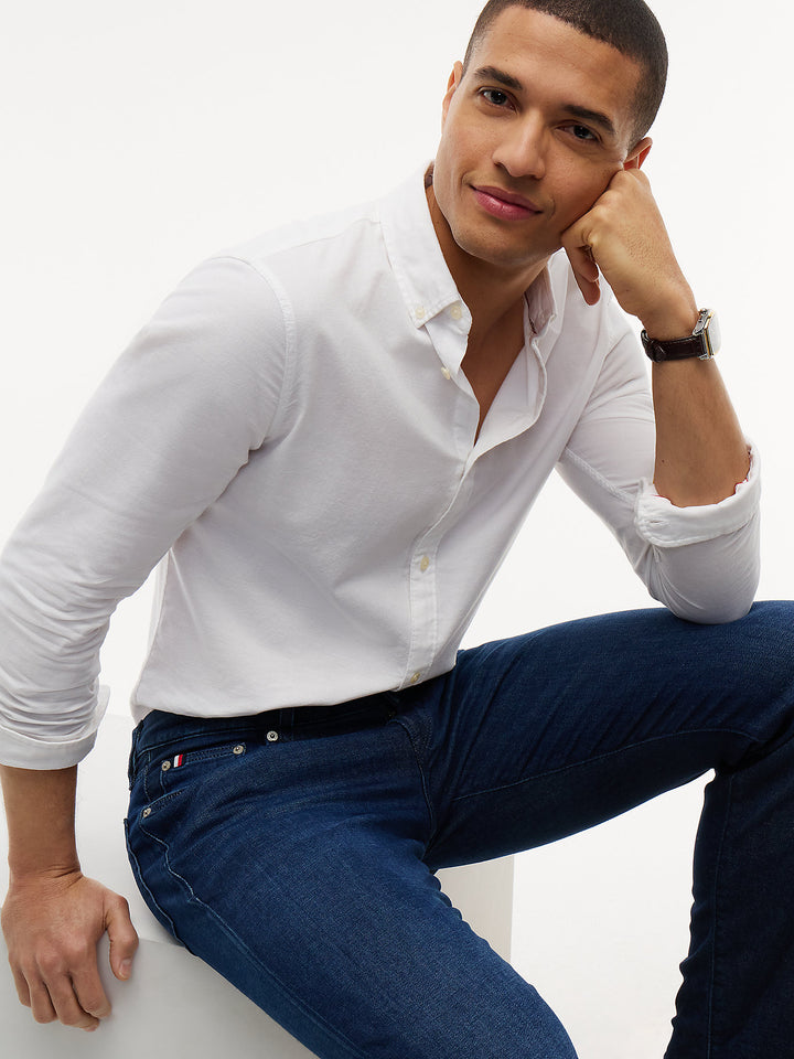 Dark blue denim slim-straight jeans, close-up of waistband, button, and front pockets