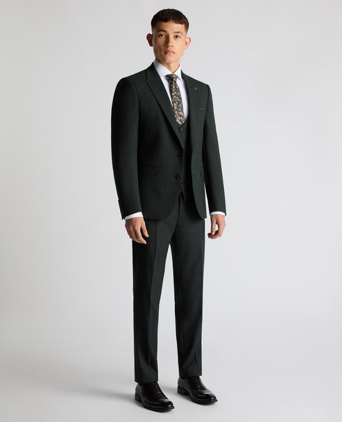 Dark green suit jacket worn with matching trousers and patterned tie