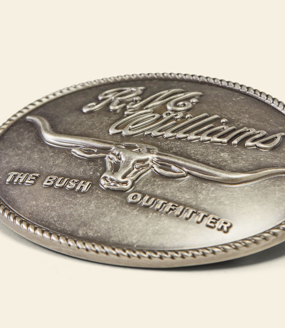 Close-up of silver circular buckle with RM Williams logo and The Bush Outfitter text