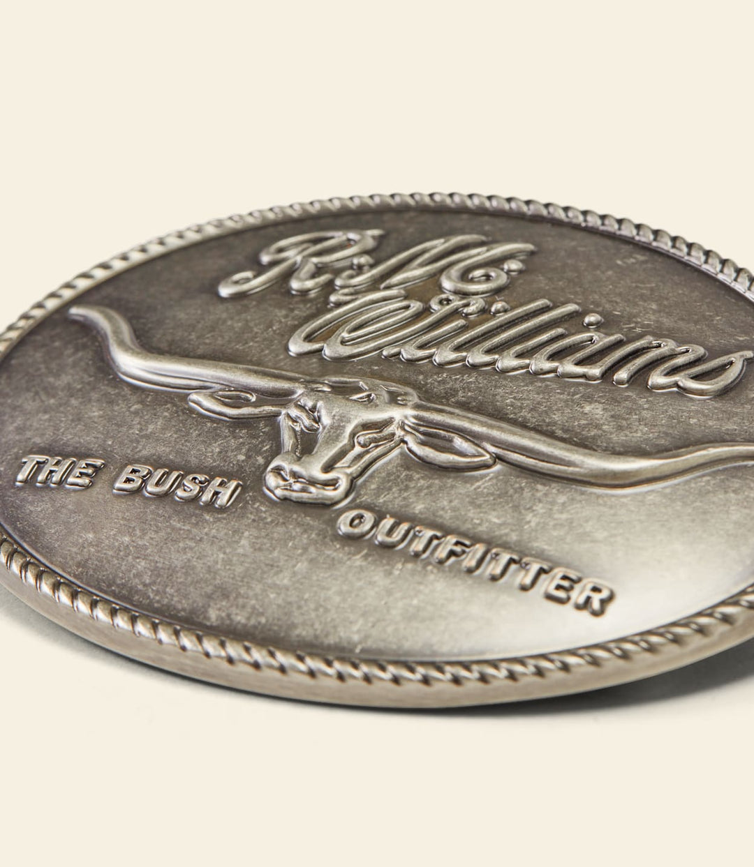 Close-up of silver circular buckle with RM Williams logo and The Bush Outfitter text
