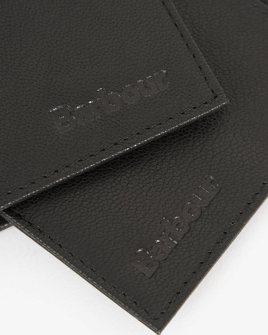 Black leather card holder close-up with stitched logo patch on flap