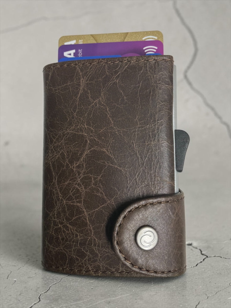 Brown leather wallet with stitched front pocket and round logo snap closure